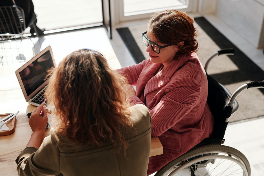 lady-on-wheel-chair-looking-at-screen-shown-to-her-by-support-lady
